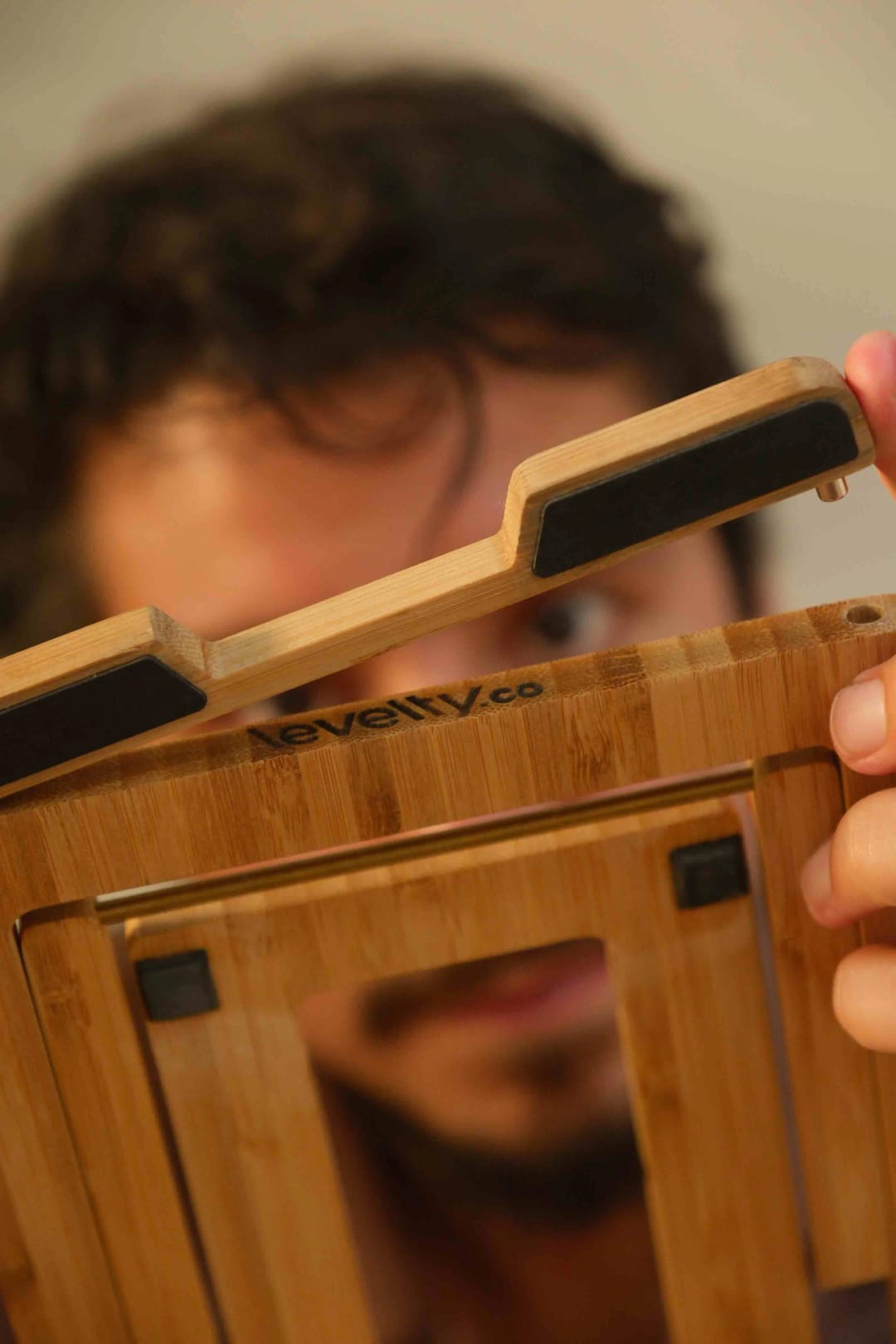 Close-up of the folded Levelty bamboo stand being opened by hand
